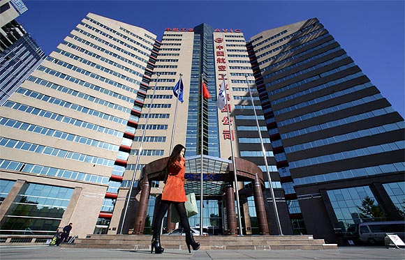 A woman walks past the Aviation Industry Corporation of China headquarters building in Beijing