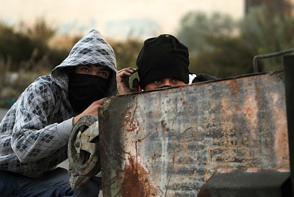 Palestinian stone-throwers take cover behind a garbage bin during clashes with Israeli security forces outside Ofer prison near the West Bank city of Ramallah