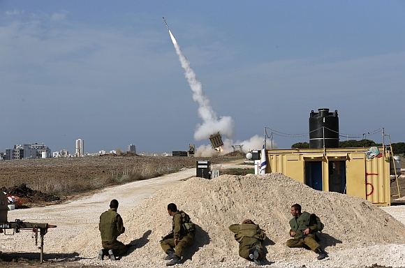 Israeli soldiers watch as an Iron Dome launcher fires an interceptor rocket near the southern city of Ashdod