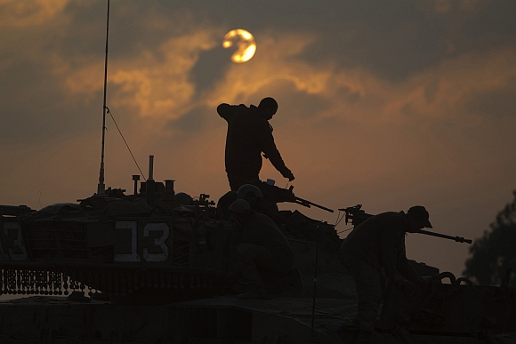 Israeli soldiers prepare a tank near Israel's border with the central Gaza Strip