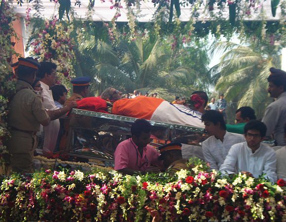 Uddhav Thackeray's son Aditya, right, looks on as Bal Thackeray's funeral procession passes through Mumbai on Sunday