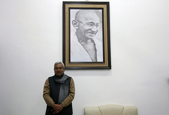 Bihar's chief minister and leader of Janata Dal United party Nitish Kumar poses in front of a portrait of Mahatma Gandhi