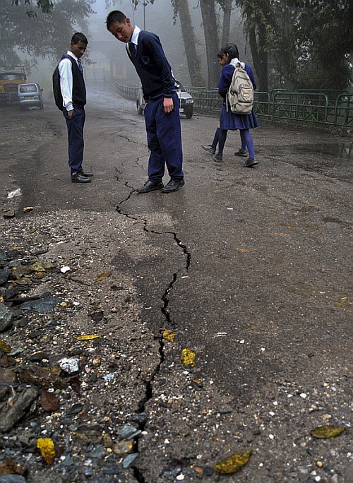 Schoolboys stop to look at a crack running down a road following a 6.9 magnitude earthquake in Gangtok, Sikkim