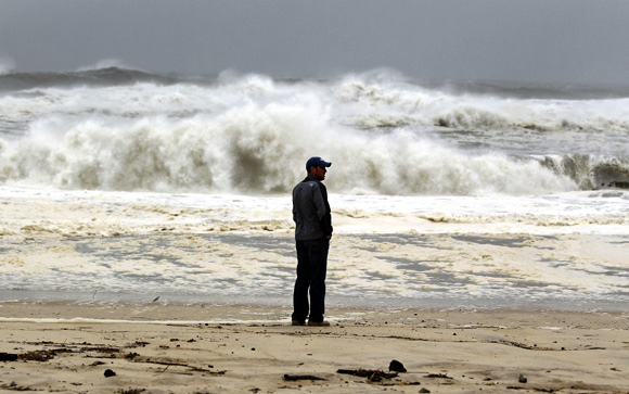A man stands on the beach to watch the storm surf, kicked up ahead of Hurricane Sandy, in Southampton, New York