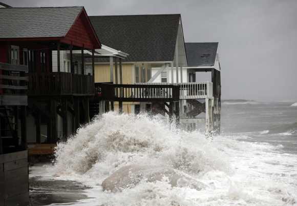 A wave crashes over the protecting sandbags in front of the houses on the east side of Ocean Isle Beach during Hurricane Sandy in Ocean Isle Beach, North Carolina