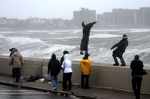 People brave high winds and waves along Winthrop Shore Drive as Hurricane Sandy comes up the coast on October 29, 2012 in Winthrop, Massachusetts