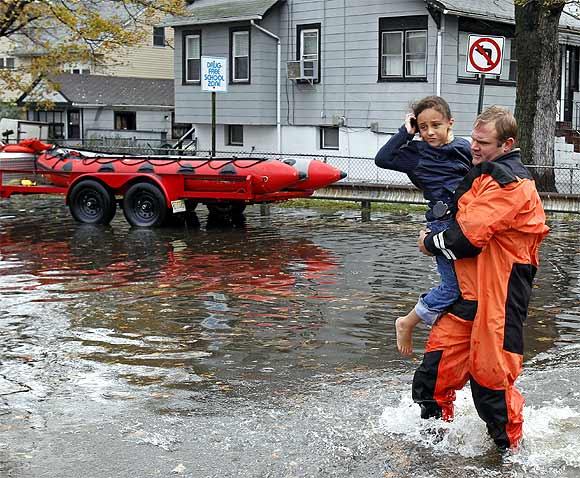 A rescue worker carries a young girl to safety from flood waters brought on by Hurricane Sandy