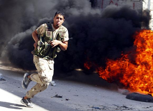 A Free Syrian Army fighter runs across a street dodging Syrian army bullets in El Amreeyeh neighbourhood of Syria's northwest city of Aleppo