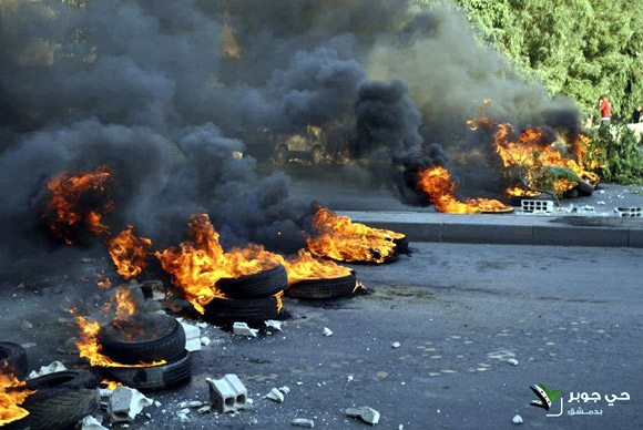 Tyres set on fire by demonstrators block a road during a protest against Syria's President Bashar al-Assad in Jubar near Damascus