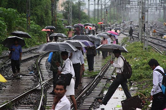 People crossing tracks in Kalyan after rains brought the trains to a halt