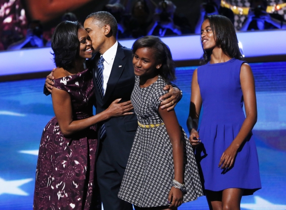 US President Barack Obama is joined on stage by First Lady Michelle Obama along with daughters Sasha and Malia