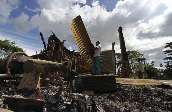 A villager searches for his belongings amid the debris of his burnt tailoring shop in Kokrajhar town on July 25