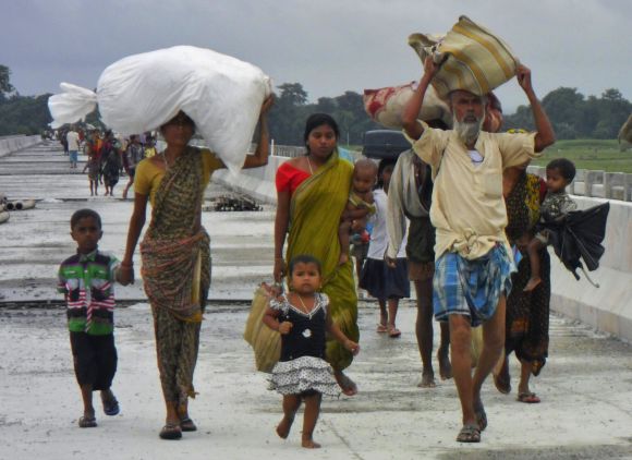 Villagers with their belongings move to relief camps as they leave their locality after violence in Assam