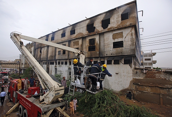 Members of City Fire Services use an aerial lift to move a dead body recovered from the building