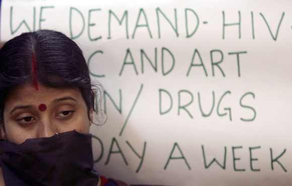 A HIV/AIDS affected Indian woman stands next to a placard during a demonstration to demand medicines for HIV-infected people