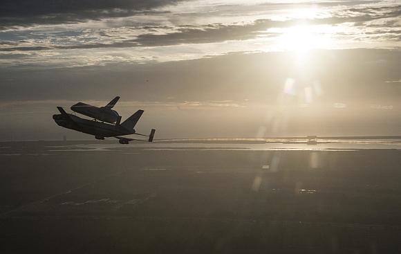 The space shuttle Endeavour, atop NASA's Shuttle Carrier Aircraft, flies over the Kennedy Space Center in Cape Canaveral, Florida