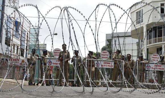 Policemen stand guard behind a coil of concertina wire setup to stop people from protesting against Sri Lankan President Mahinda Rajapaksa