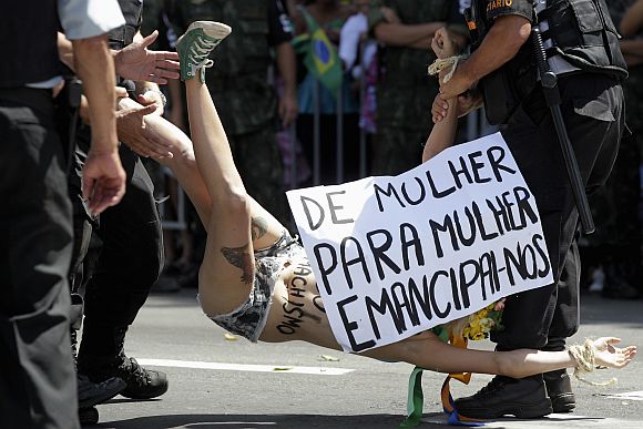 Police officers detain a protester in support of women's rights group Femen, during a civic-military parade commemorating the Independence Day of Brazil in Brasilia September 7, 2012. Sign reads, From woman to woman, emancipate ourselves