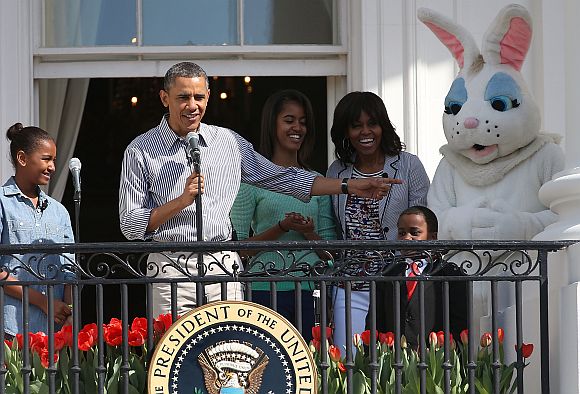 US President Barack Obama speaks while flanked by his daughters Sasha (L), Malia, first lady Michelle Obama, Robby Novak and the Easter Bunny, during the annual Easter Egg Roll on the White House tennis court April 1