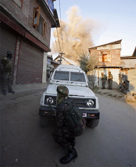 A soldier takes cover as a residential house is blown up by an improvised explosive device during a gun battle between army and suspected militants in Sopore, 48km north of Srinagar