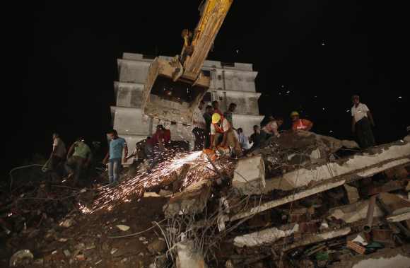 Rescue workers use a cutting tool to search for survivors after the building collapse in Thane
