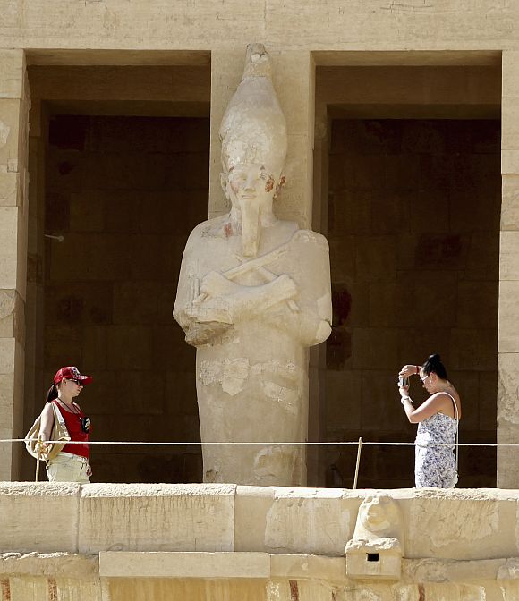 A tourist takes a photo of her sister at the Temple of Hatshepsut in Luxor