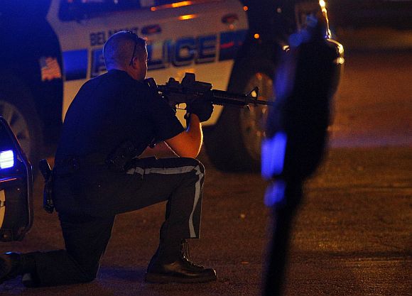 A police officer points his rifle at a man (not pictured) on the ground in Watertown