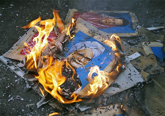 Portraits of Prime Minister Manmohan Singh and Congress President Sonia Gandhi lie in flames after they were set on fire by demonstrators during a protest