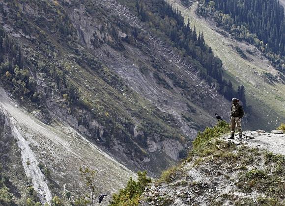 An Indian army soldier keeps guard on a mountainous road before the foundation stone laying ceremony for a tunnel on the Srinagar-Leh highway in Zojila, 108 km east of Srinagar