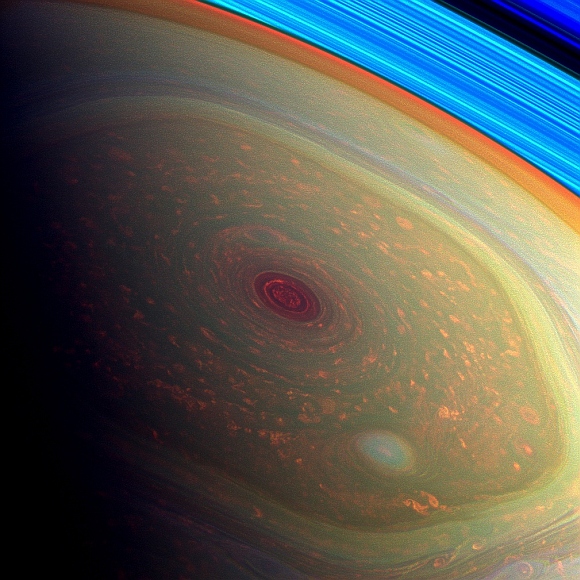 This spectacular, vertigo inducing, false-color image from NASA's Cassini mission highlights the storms at Saturn's north pole. The angry eye of a hurricane-like storm appears dark red while the fast-moving hexagonal jet stream framing it is a yellowish green. Low-lying clouds circling inside the hexagonal feature appear as muted orange color. A second, smaller vortex pops out in teal at the lower right of the image.