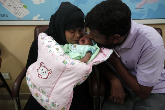 A childless couple kisses their newly adopted daughter, Fatima, whom Pakistani television talk show host Aamir Liaquat Hussain gave them on his show, as they sit at the Chhipa Welfare Association office in Karachi 