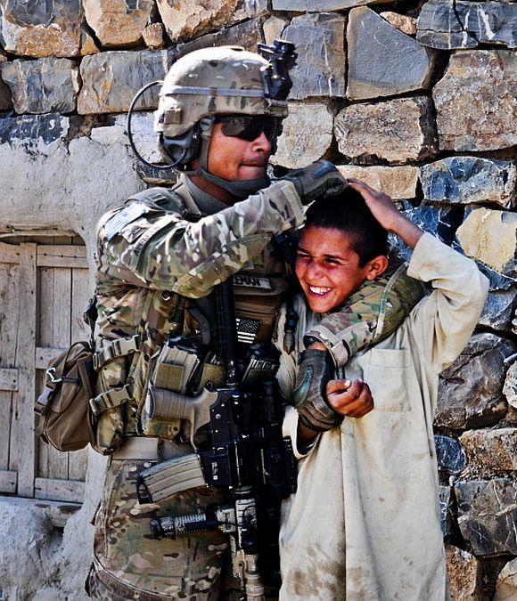 United States Army Staff Sergeant Christian Aleman, from Miami, a squad leader assigned to A Battery, gives a playful nudge to a Afghan boy while out on patrol