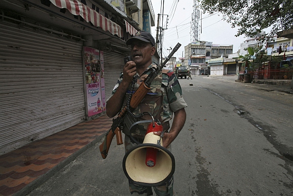 An army soldier makes an announcement to the public to stay indoors during a curfew in Jammu