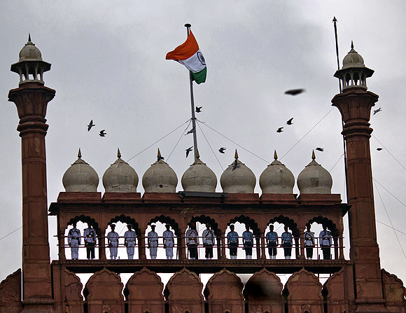 Buglers from India's armed forces stand on the balcony of the historic Red Fort as the Indian national flag flutters during the full-dress rehearsal for India's Independence Day celebrations in Delhi 