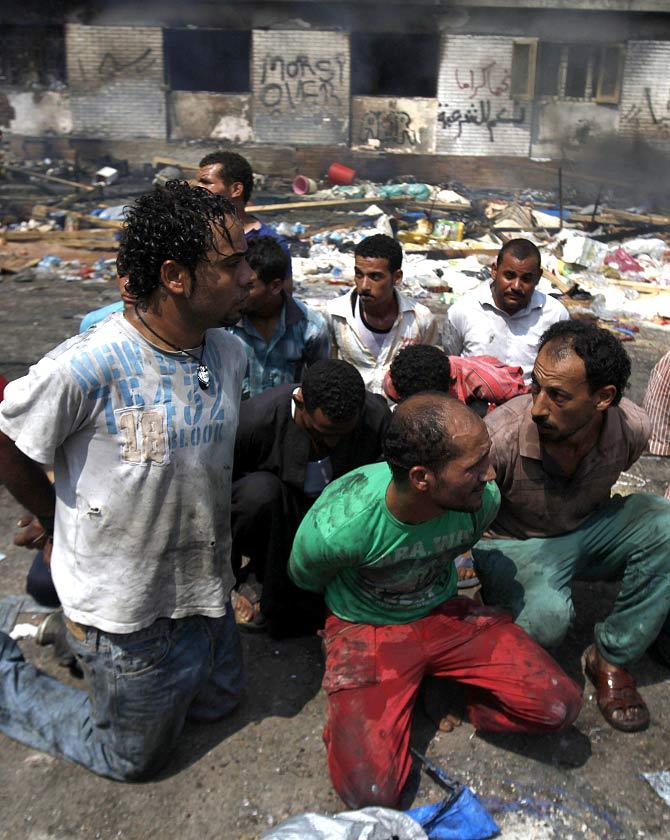 Suspects are rounded up near a burnt annex building of Rabaa Adawiya mosque after the clearing of a protest camp around the mosque, in Cairo