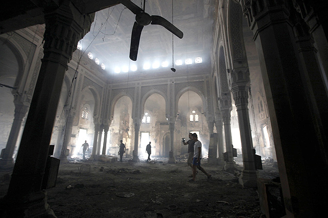 People walk inside the burnt Rabaa Adawiya mosque, the morning after the clearing of a protest  which was held around the mosque