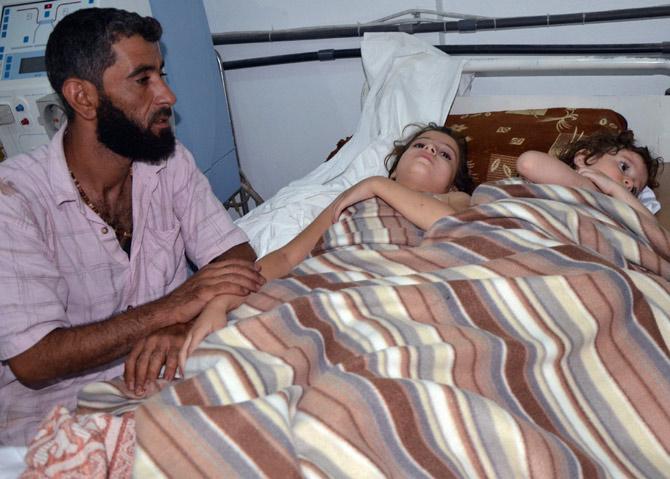 A man sits in a hospital near two children who activists say were affected by nerve gas in the Ghouta region, in the Duma neighbourhood of Damascus