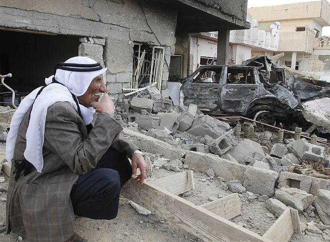 A man smokes a cigarette as he sits at the site of a bomb attack in Kirkuk