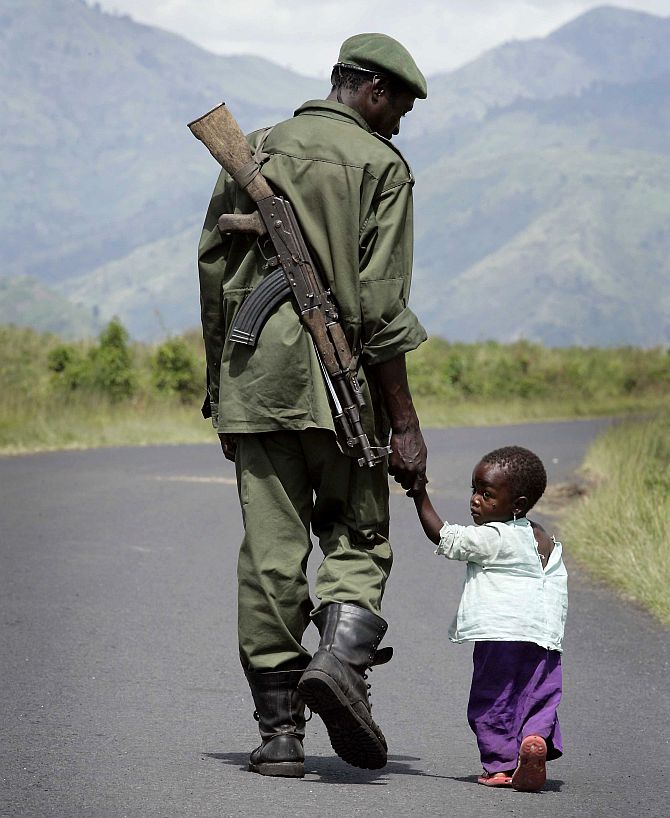 A Congolese Government soldier walks on the road towards Sake holding his daughter's hand, near the city of Goma in eastern Congo