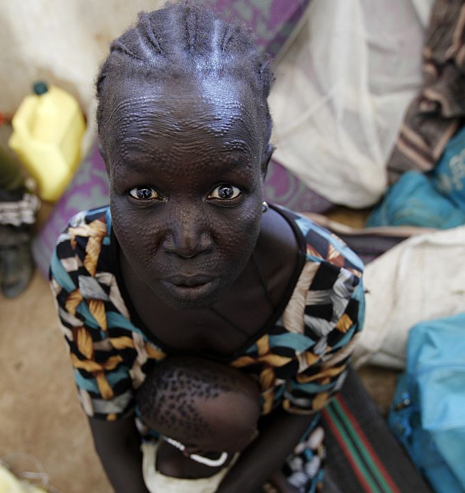 A refugee woman from Jonglei State in South Sudan sits inside a temporary shelter with her child at the registration centre in a refugee camp