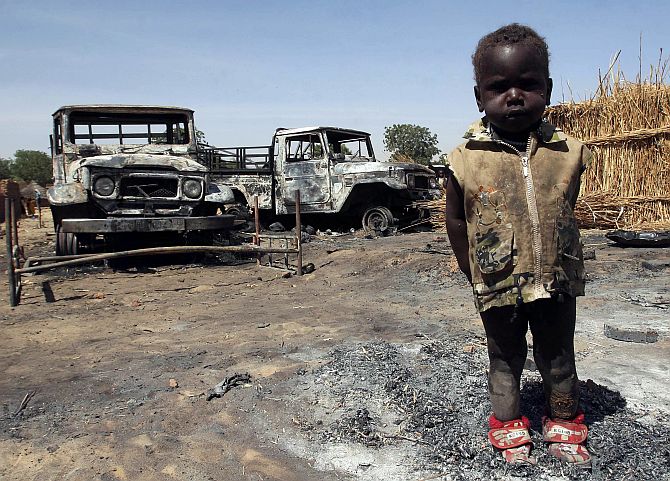 A child stands in front of cars burned during the rebels' last attack in Adre