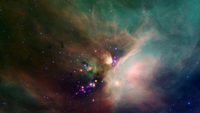Newborn stars peek out from beneath their natal blanket of dust in this dynamic image of the Rho Ophiuchi dark cloud from NASA's Spitzer Space Telescope