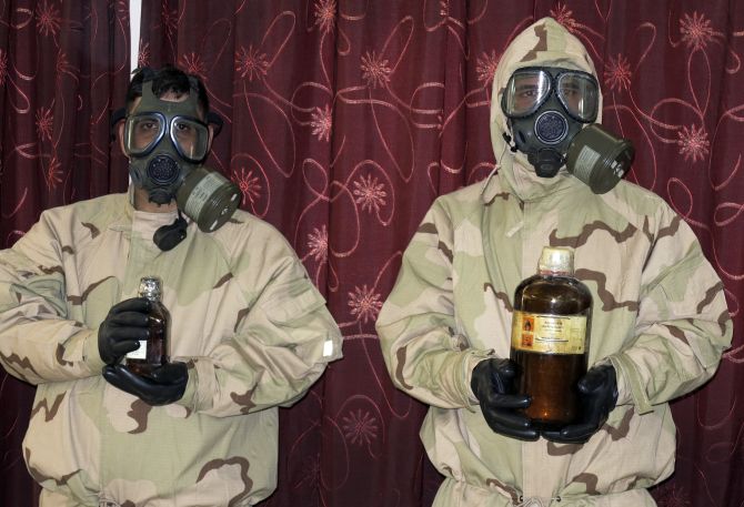Soldiers wearing gas masks hold bottles containing chemical materials during a news conference at the Defence Ministry in Baghdad 