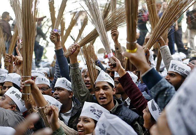 Aam Aadmi Party workers celebrate with brooms, the party symbol, after the AAP's historic mandate in the Delhi assembly election.