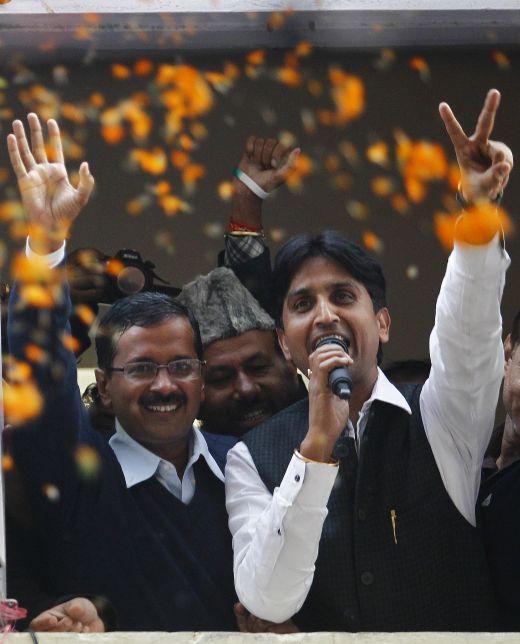 AAP leaders Arvind Kejriwal and Kumar Vishwas wave to their supporters after an emphatic performance in the Delhi polls, on Monday