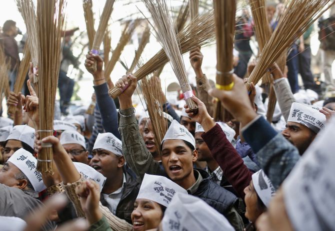 Supporters of Aam Aadmi Party, hold brooms, the party's symbol, as they celebrate their performance in the Delhi assembly elections