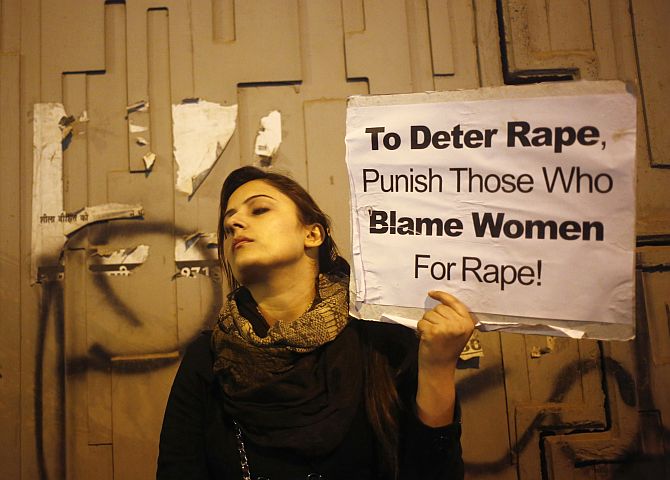 A demonstrator holds a placard as she attends a candlelight vigil to mark the first anniversary of Delhi gang rape