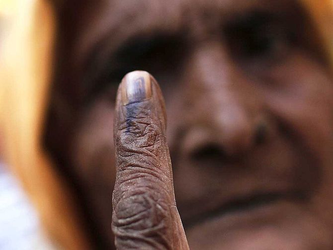 A woman shows her ink-marked finger after casting her vote.