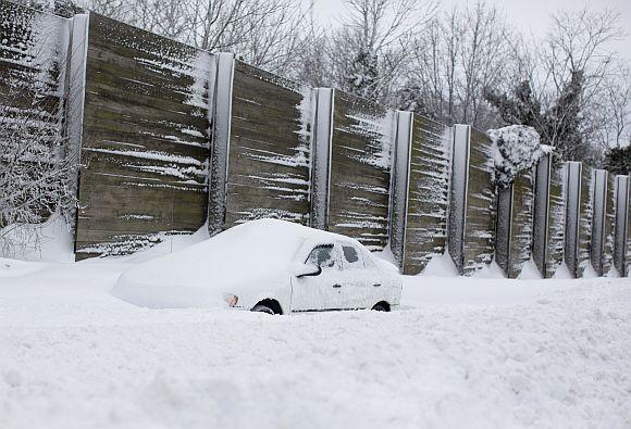 A man shovels snow from the sidewalk on the Upper East Side of New York