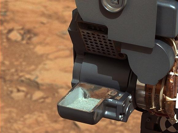 This image from NASA's Curiosity rover shows the first sample of powdered rock extracted by the rover's drill. The image was taken after the sample was transferred from the drill to the rover's scoop